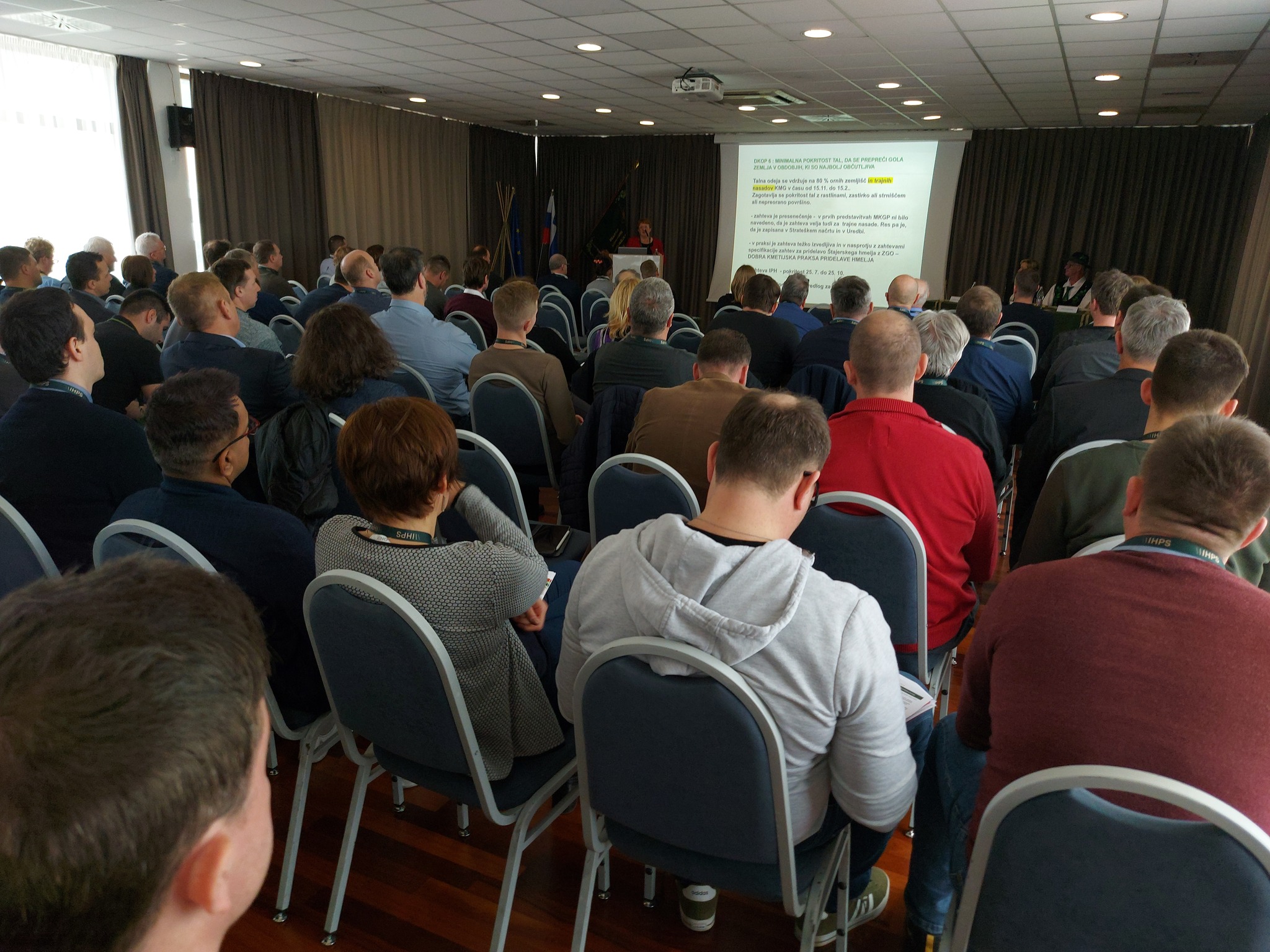 Skupinska slika udeležencev, ki sedijo na stolih in gledajo predstavitev.