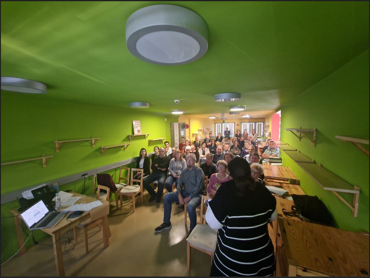 Udeleženci sedijo na stolih v dvorani